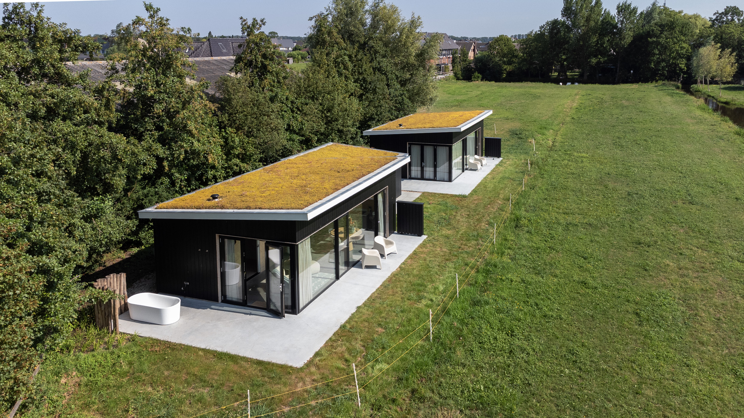 Twee vakantiewoningen met groendaken in polderlandschap vogelperspectief