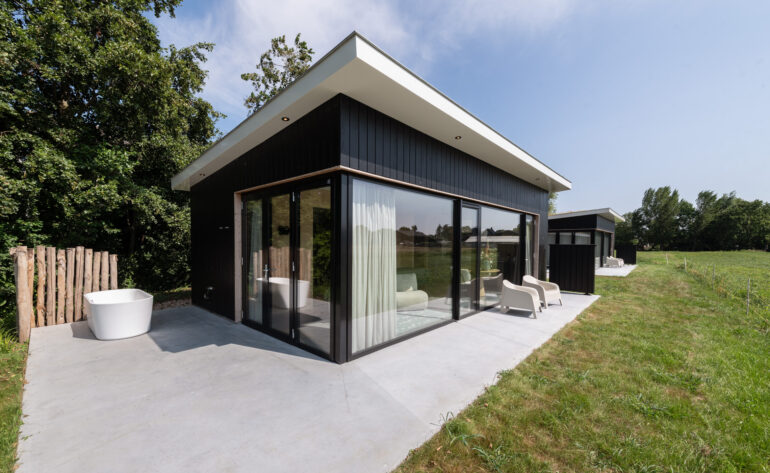 Zwarte vakantiewoning met houten omlijsting van raampartij