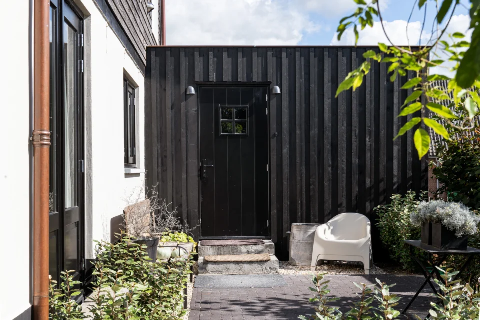 LvdP 20250923 2243 Uitbreiding woning in contrast met het witte stucwerk van het hoofdgebouw.