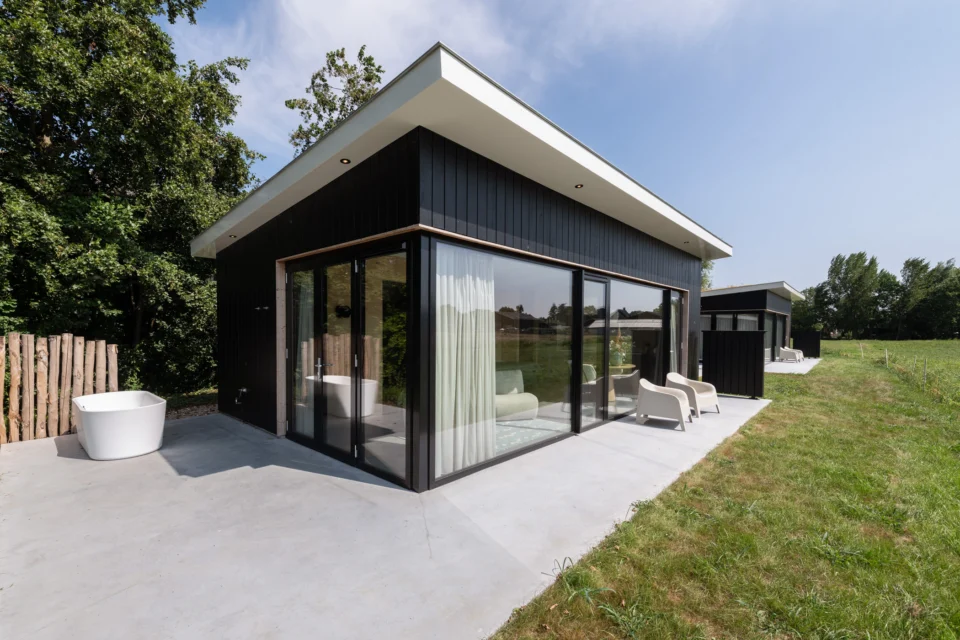 Zwarte vakantiewoning met houten omlijsting van raampartij